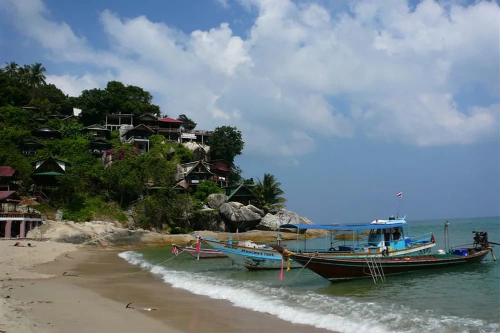 Longtail boats pulled up on Than Sadet beach below bungalows built into the rocks.